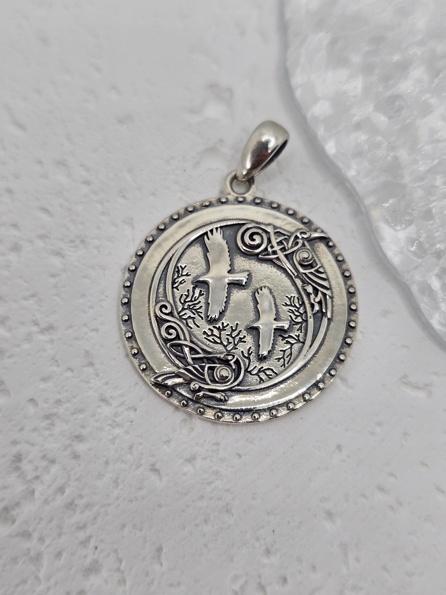 Step into the mystic shadows of the ancient forest with this Viking Crow Medallion, forged from solid 925 sterling silver and brought to life with deep symbolism and fine detail. At the heart of the design stand Huginn and Muninn, Odin’s trusted ravens, surrounded by an enchanted woodland scene carved into silver—a tribute to Norse mythology and the pursuit of knowledge.
Encircling the forest and birds is a ring of Norse runes, each symbol a whisper of ancient magic, representing insight, wisdom, and the u