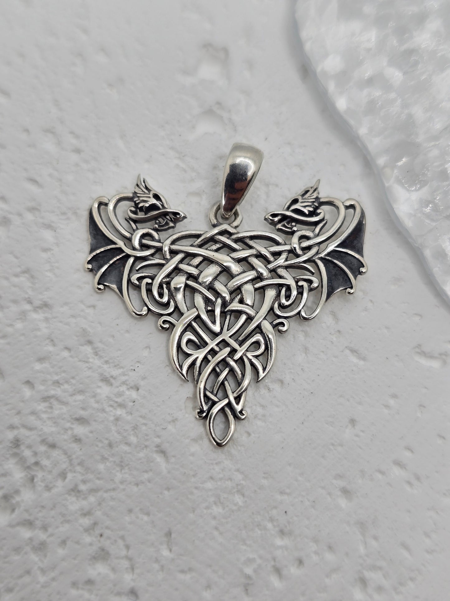 Step into the realm of legend with this Twin Dragons Pendant, crafted from solid 925 sterling silver and steeped in the ancient spirit of Celtic myth and romance. Two dragons, symbols of strength and loyalty, curl around one another in perfect symmetry, their entwined forms shaping a heart—representing love, unity, and unbreakable bonds.
Framing the dragons is intricate Celtic knotwork, a pattern without beginning or end, reflecting the eternal cycles of life and the enduring nature of love and connection.