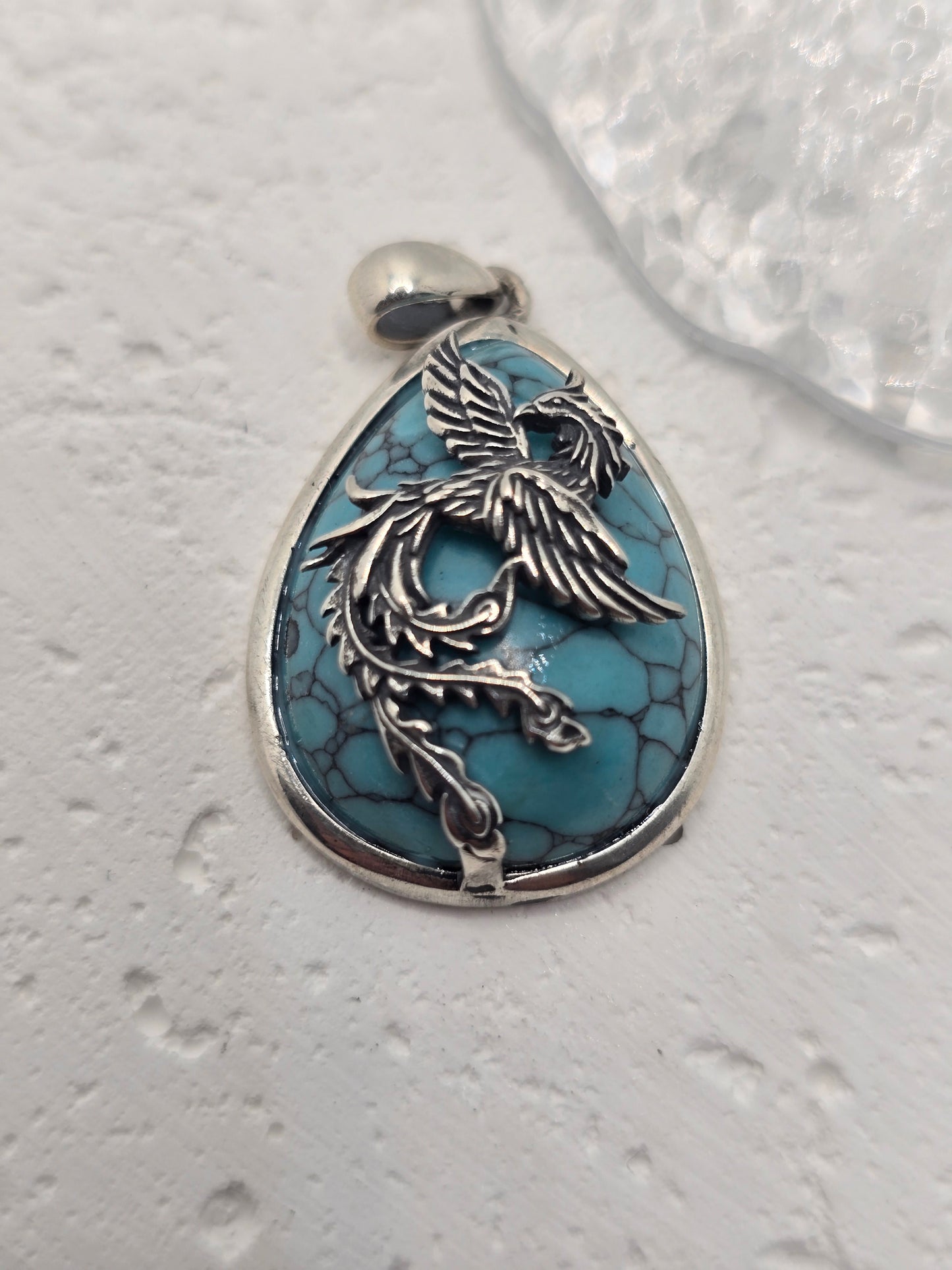 Embrace transformation and rise renewed with the Rebirth Phoenix Pendant, a striking talisman crafted in 925 sterling silver and inlaid with vibrant turquoise. This dynamic pendant captures the eternal spirit of the phoenix, a mythical bird that is reborn from its ashes, symbolizing resilience, renewal, and the power of personal evolution.
With outstretched wings and flowing form, the phoenix is depicted mid-flight—ascending, powerful, and full of life. The turquoise gemstone, with its calming blue hue, re