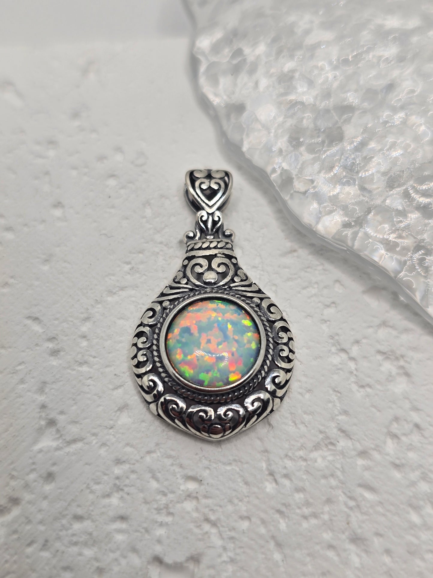 Celebrate timeless romance with this Vintage Style Heart Pendant, masterfully crafted from 925 sterling silver and set with a glowing 2.5ct cabochon opal. With its soft, iridescent shimmer, the opal captures light like a whispered secret, echoing the elegance of a bygone era.
The pendant’s vintage-inspired design features delicate heart motifs and ornate silverwork, making it both a romantic symbol and a bold statement piece. The opal is expertly bezel-set within an intricate frame, polished to a high shin