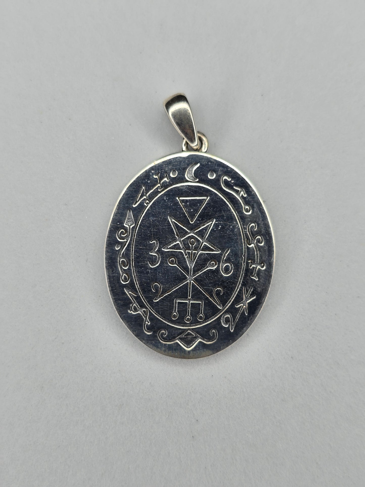 Back view of sterling silver occult pendant with engraved sigil and textured finish