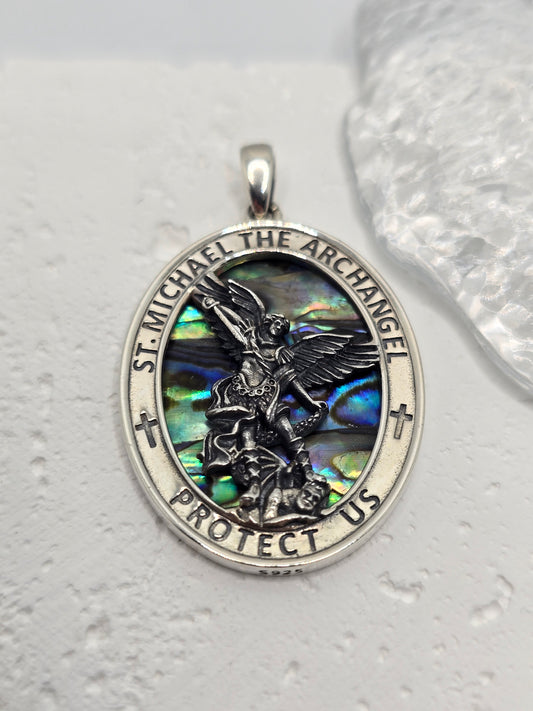 Saint Michael Archangel with Shell Inlay in Precious Metal
A powerful emblem of protection and courage, this Saint Michael Archangel pendant is crafted in 925 sterling silver and set against an iridescent shell inlay that shimmers with changing colours. Hallmarked for authenticity, it’s a meaningful devotional piece and a refined everyday pendant.

Design & Symbolism

    Saint Michael the Archangel: Defender and protector, triumphing over evil.

    Protective Inscription: “Saint Michael the Archangel Prot