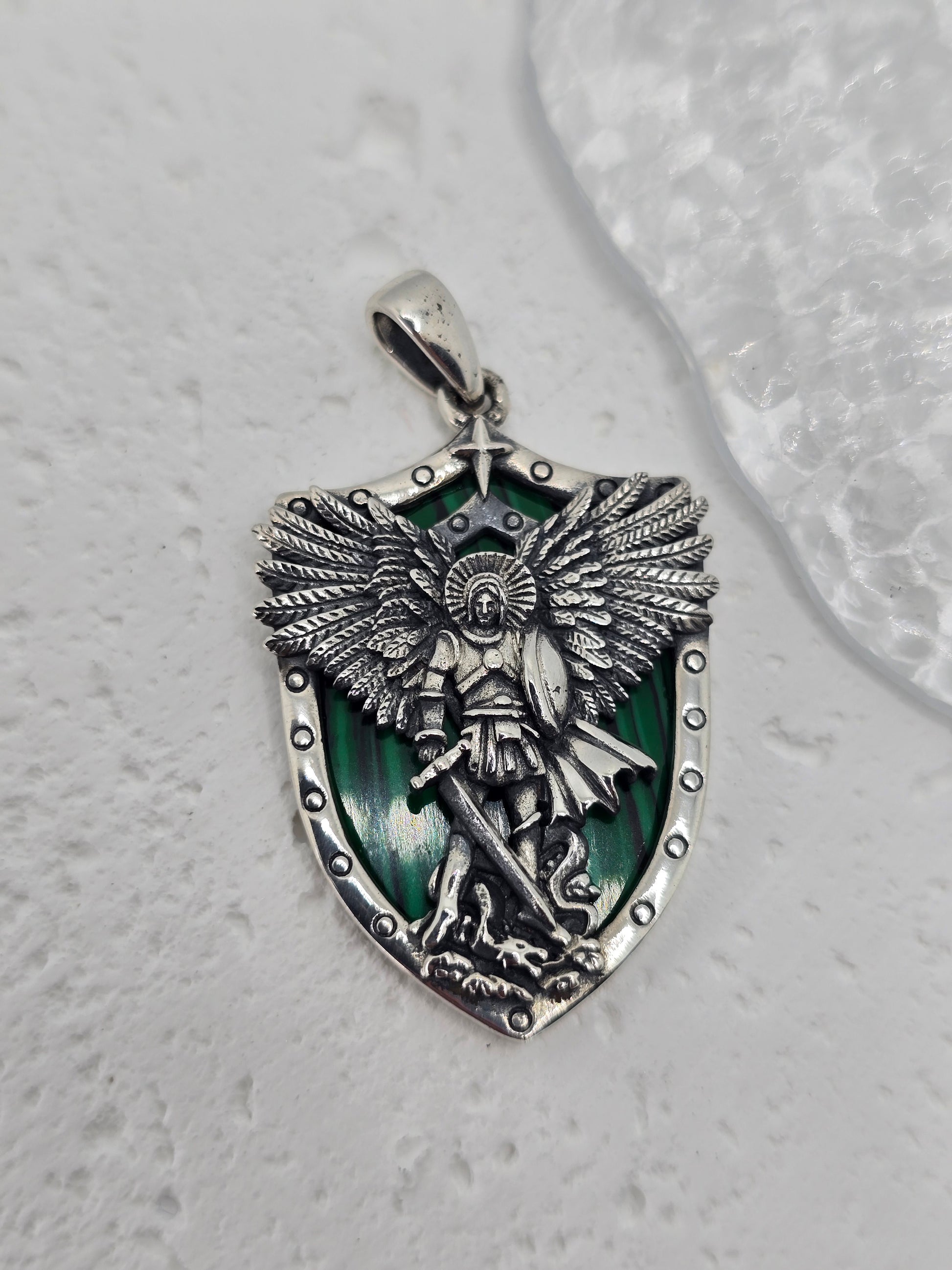 Saint Michael Archangel Protection with Malachite in 925 Sterling Silver
A powerful symbol of courage and guardianship, this Saint Michael pendant is crafted in 925 sterling silver with a rich malachite shield backdrop. Depicting the Archangel standing over a vanquished foe, it’s a meaningful devotional piece and a refined everyday pendant. A single star above the figure symbolizes hope and divine guidance.

Design &amp; Symbolism

Saint Michael the Archangel: Defender and protector, triumphing over evil.
M
