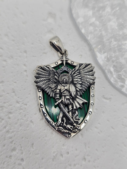 Saint Michael Archangel Protection with Malachite in 925 Sterling Silver
A powerful symbol of courage and guardianship, this Saint Michael pendant is crafted in 925 sterling silver with a rich malachite shield backdrop. Depicting the Archangel standing over a vanquished foe, it’s a meaningful devotional piece and a refined everyday pendant. A single star above the figure symbolizes hope and divine guidance.

Design &amp; Symbolism

Saint Michael the Archangel: Defender and protector, triumphing over evil.
M