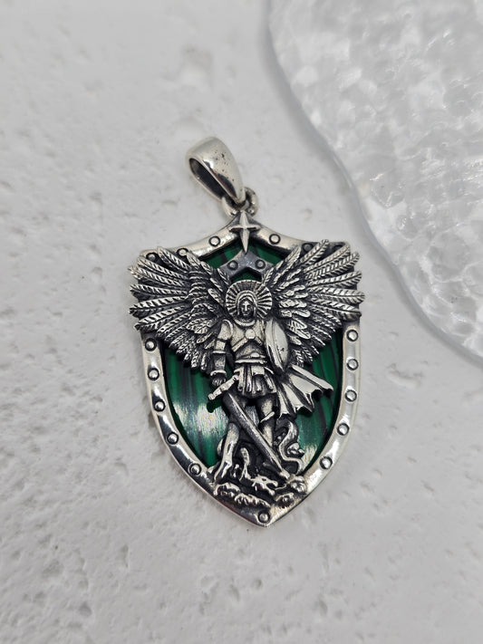 Saint Michael Archangel Protection with Malachite in 925 Sterling Silver
A powerful symbol of courage and guardianship, this Saint Michael pendant is crafted in 925 sterling silver with a rich malachite shield backdrop. Depicting the Archangel standing over a vanquished foe, it’s a meaningful devotional piece and a refined everyday pendant. A single star above the figure symbolizes hope and divine guidance.

Design &amp; Symbolism

Saint Michael the Archangel: Defender and protector, triumphing over evil.
M