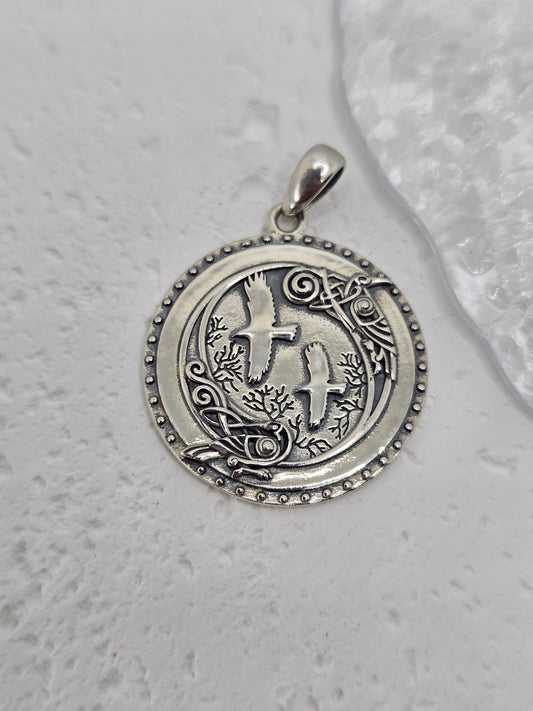 Step into the mystic shadows of the ancient forest with this Viking Crow Medallion, forged from solid 925 sterling silver and brought to life with deep symbolism and fine detail. At the heart of the design stand Huginn and Muninn, Odin’s trusted ravens, surrounded by an enchanted woodland scene carved into silver—a tribute to Norse mythology and the pursuit of knowledge.

Encircling the forest and birds is a ring of Norse runes, each symbol a whisper of ancient magic, representing insight, wisdom, and the u