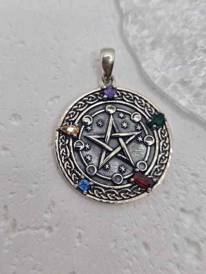 Unlock the power of cosmic energy and elemental balance with this Pentagram Cosmic Cycle Amulet, beautifully crafted from 925 sterling silver and set with vibrant chakra gemstones. This mystical pendant merges the ancient power of the pentagram with the cyclical wisdom of the lunar phases, creating a talisman that protects, empowers, and aligns the spirit.

At the center lies a classic five-pointed star, long revered as a symbol of protection, spiritual knowledge, and harmony between the elements—earth, air