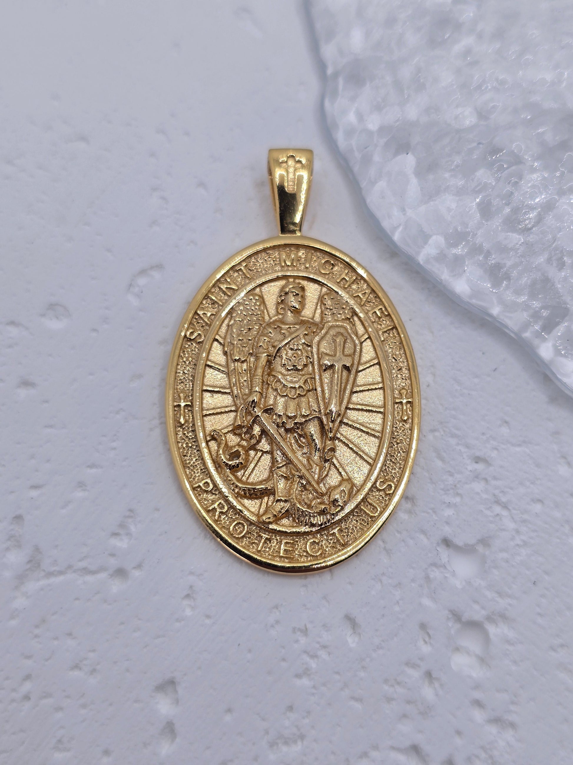 Experience the strength of divine guardianship with this powerful Saint Michael Guardian Archangel Pendant, meticulously crafted in 925 sterling silver and richly enhanced with 18K gold plating. More than just jewelry, this medal is a symbol of protection, bravery, and spiritual victory over darkness.

At the heart of the pendant stands St. Michael the Archangel, the heavenly warrior known for shielding souls from evil and leading the army of light. Clad in armor, sword raised and shield in hand, he represe