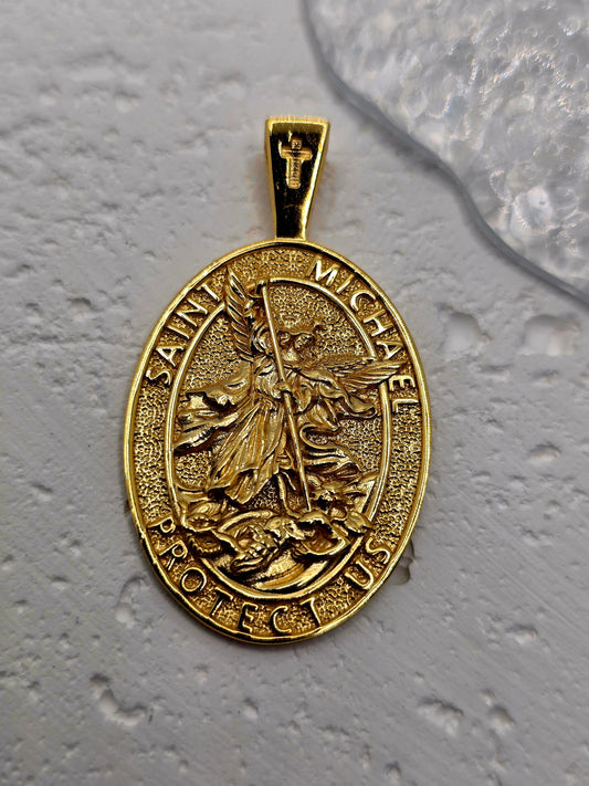 Saint Michael Protection in Precious Metal
Embrace courage and divine guardianship with the Saint Michael Protection Pendant, crafted in solid 925 sterling silver and finished with 18K gold plating. The high-relief image of Saint Michael the Archangel triumphing over evil is encircled by the invocation “Saint Michael Protect Us,” offering strength, justice, and reassurance in challenging times.

The reverse carries a devotional inscription affirming protection and faith, adding spiritual depth to this elega