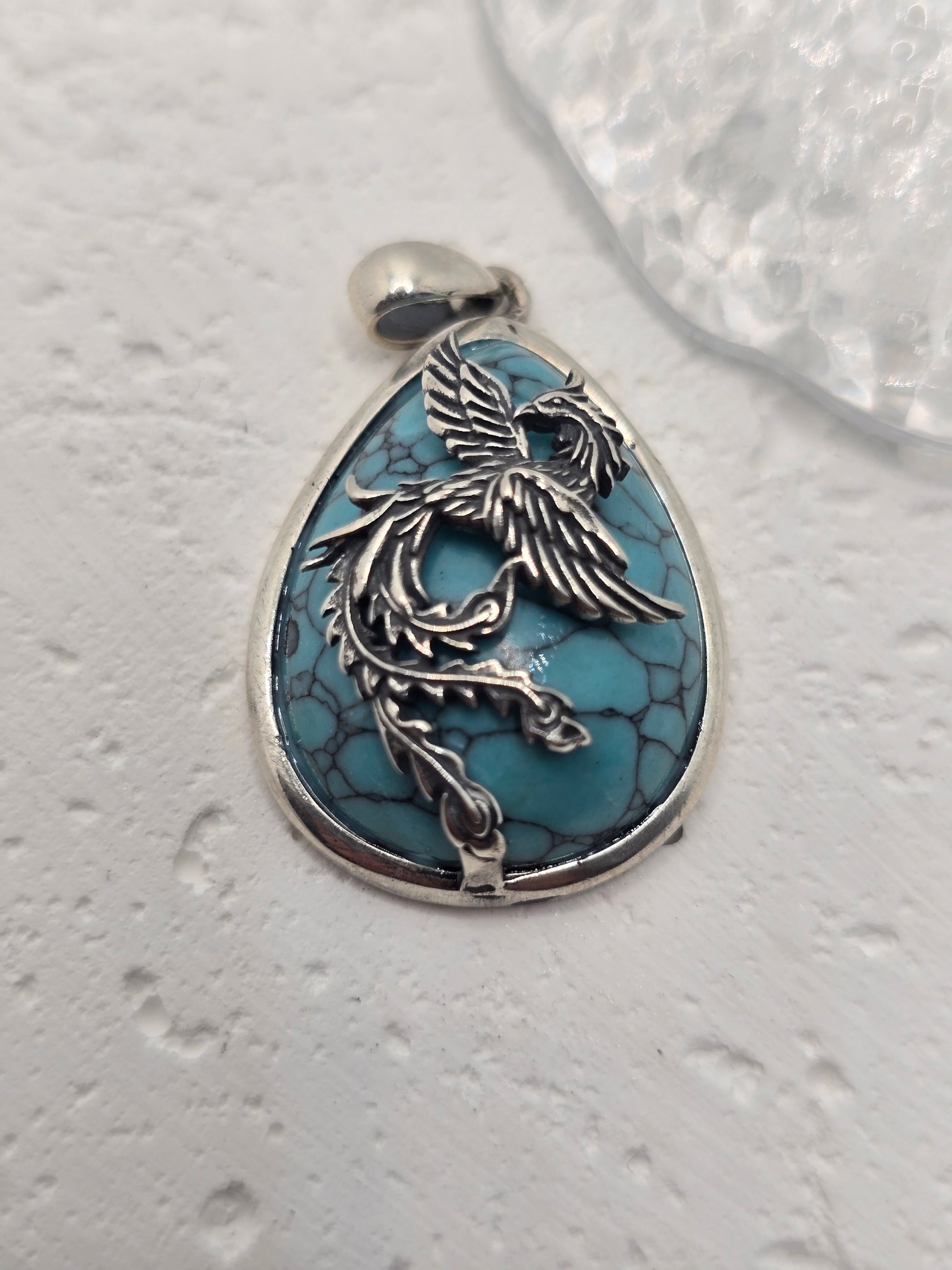 Embrace transformation and rise renewed with the Rebirth Phoenix Pendant, a striking talisman crafted in 925 sterling silver and inlaid with vibrant turquoise. This dynamic pendant captures the eternal spirit of the phoenix, a mythical bird that is reborn from its ashes, symbolizing resilience, renewal, and the power of personal evolution.

With outstretched wings and flowing form, the phoenix is depicted mid-flight—ascending, powerful, and full of life. The turquoise gemstone, with its calming blue hue, re