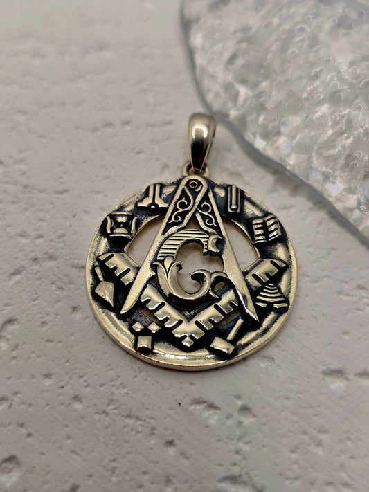 Honor tradition, craft, and symbolic protection with this Freemason Masonic Pendant, crafted in solid 925 sterling silver. At the centre stands the square and compasses, surrounded by classic Masonic tool motifs and a border of rune-inspired patterns—a thoughtful emblem of brotherly love, truth, and moral fortitude.

Refined relief work and balanced proportions give this piece a dignified presence for daily wear or ceremonial moments. Ideal for members of the fraternity, milestone gifts, or collectors of me