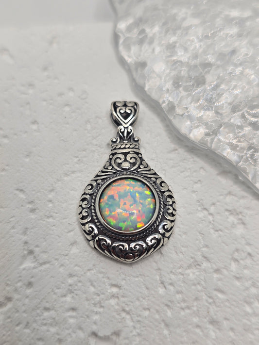 Celebrate timeless romance with this Vintage Style Heart Pendant, masterfully crafted from 925 sterling silver and set with a glowing 2.5ct cabochon opal. With its soft, iridescent shimmer, the opal captures light like a whispered secret, echoing the elegance of a bygone era.

The pendant’s vintage-inspired design features delicate heart motifs and ornate silverwork, making it both a romantic symbol and a bold statement piece. The opal is expertly bezel-set within an intricate frame, polished to a high shin