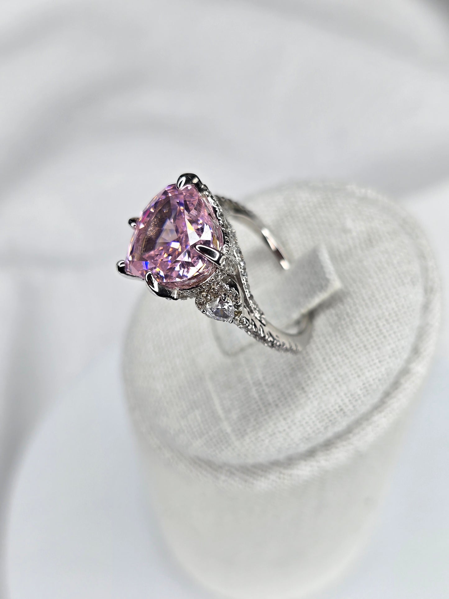 Side view of heart shaped pink moissanite ring with pavé silver band