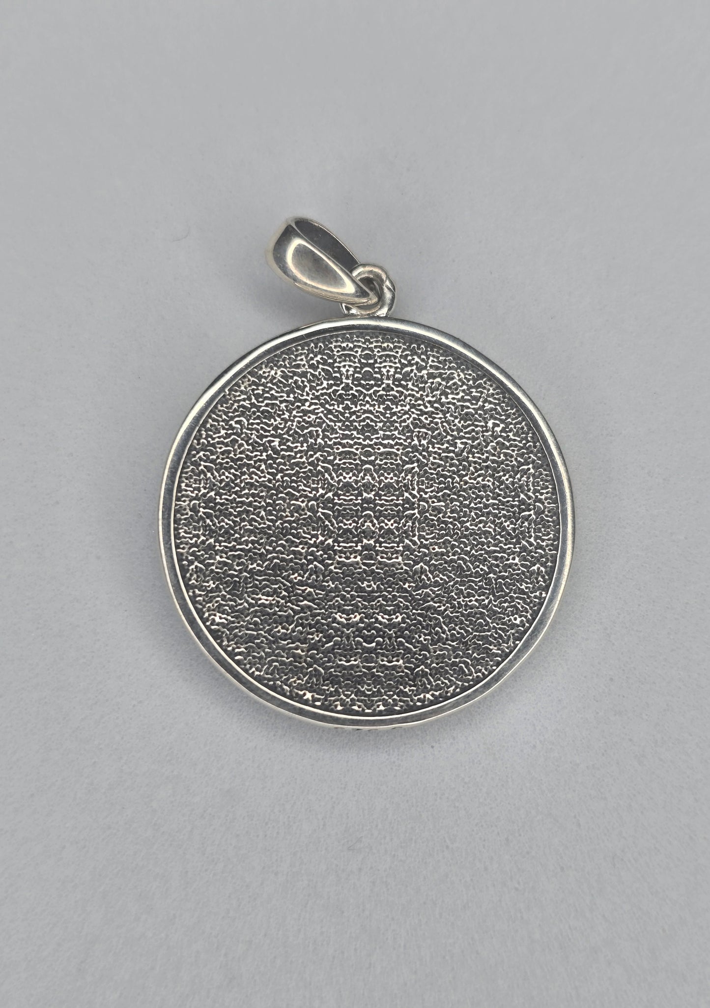 Back view of sterling silver dragon pendant with textured circular finish