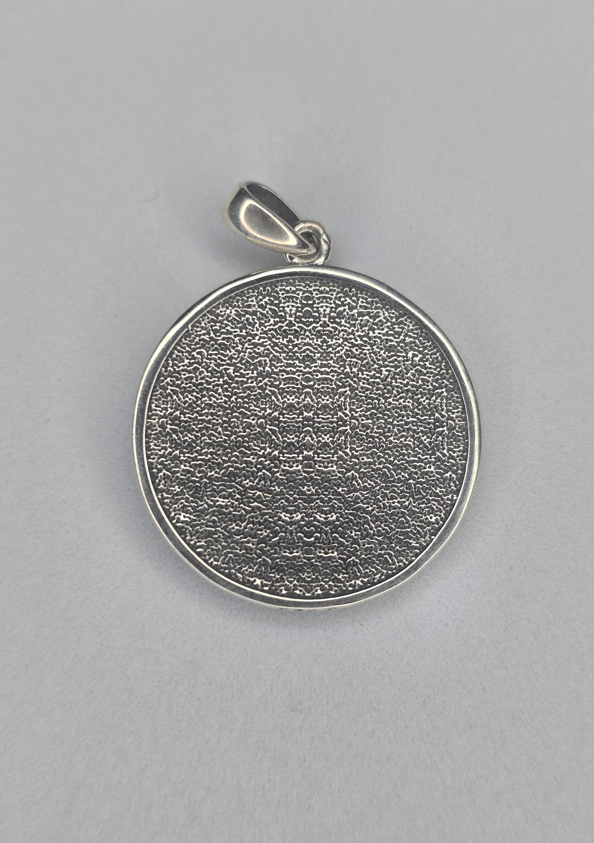 Back view of sterling silver dragon pendant with textured circular finish
