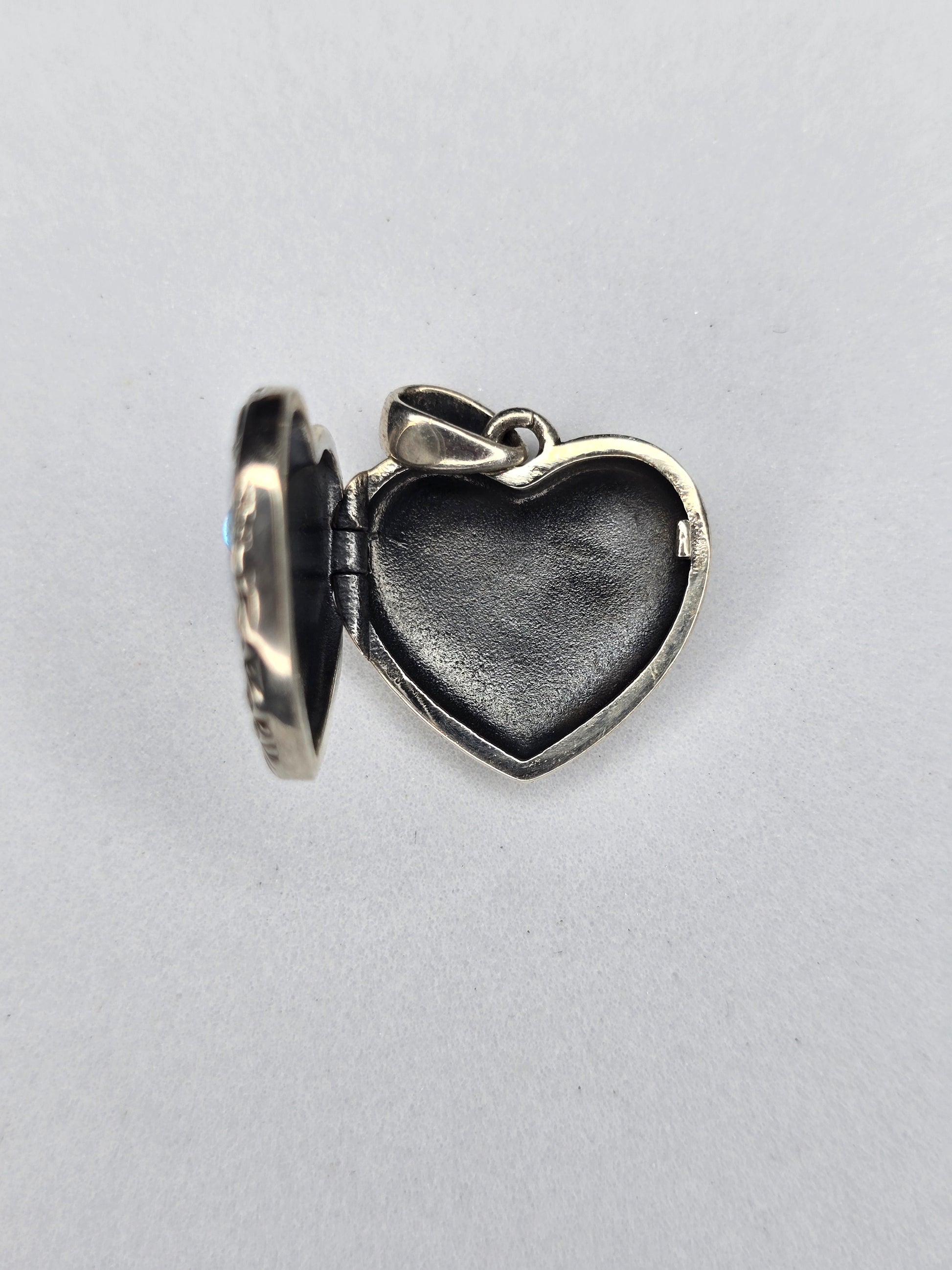 Open heart-shaped silver photo locket showing interior compartment