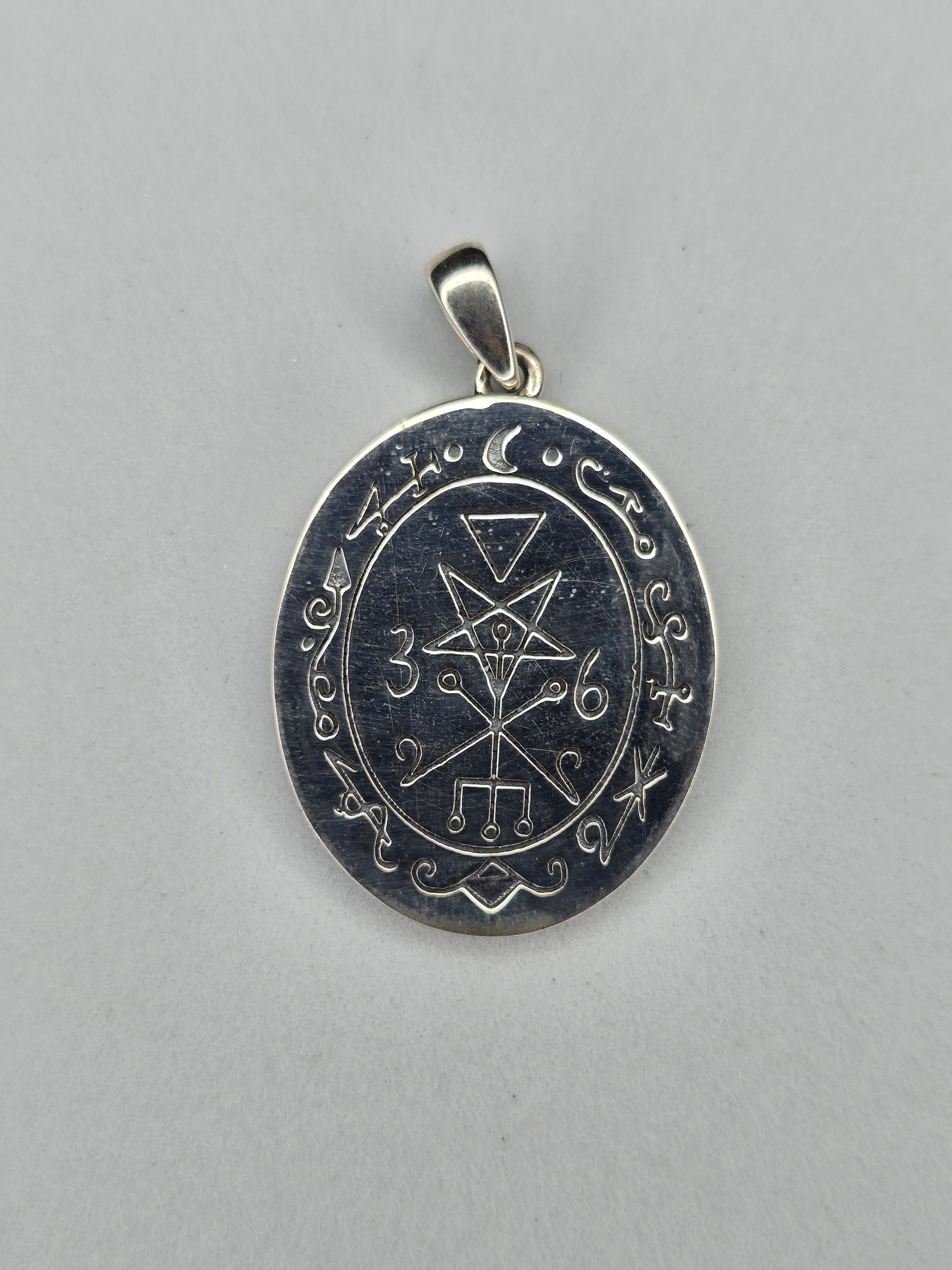 Back view of sterling silver occult pendant with engraved sigil and textured finish