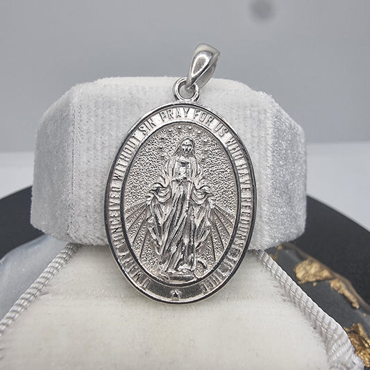 

Introducing the Virgin Mary Pendant, a beautifully crafted piece made from 925 Sterling Silver. This pendant features a detailed depiction of the Virgin Mary, making it a significant symbol of faith and devotion for religious believers.

This pendant is more than just a piece of jewelry; it's a representation of deep faith and spiritual reverence. The front of the pendant showcases the Virgin Mary with rays of light emanating from her, symbolizing purity, grace, and divine love. The inscription around the